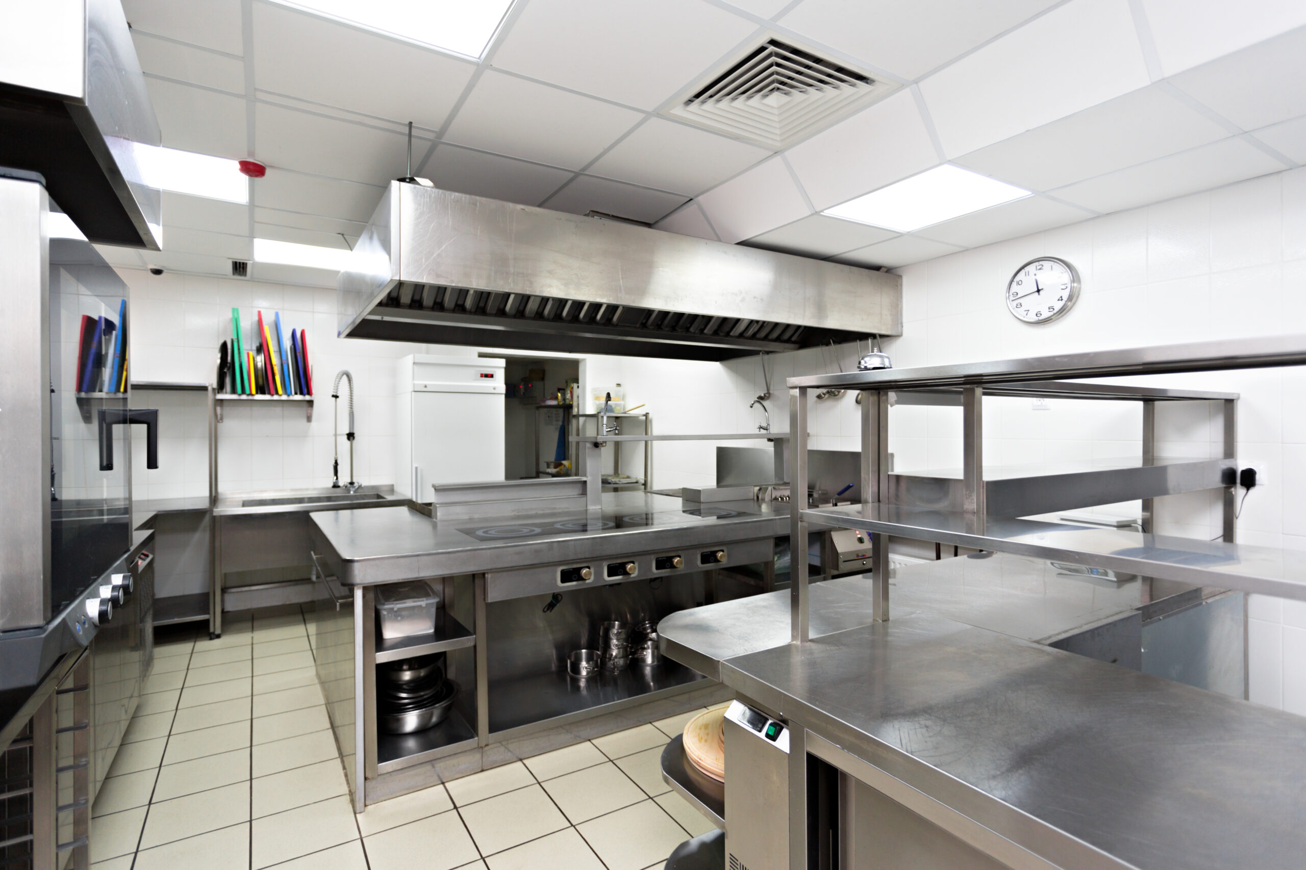 Clean stainless steel work surfaces and equipment in a commercial kitchen